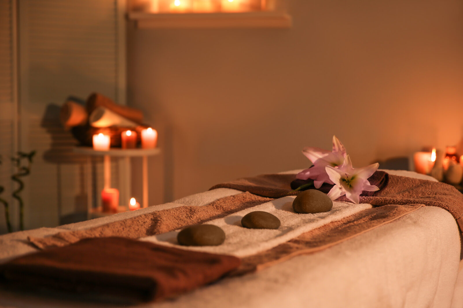 A calm treatment table set with smooth stones and a flower